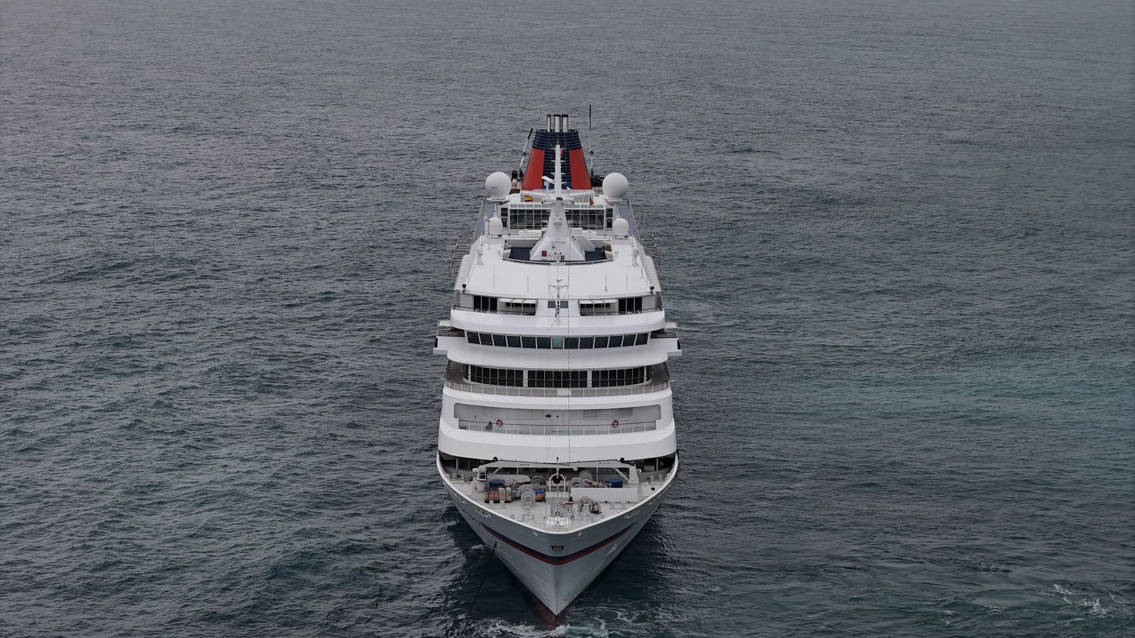 Aerial view of a white cruise ship sailing straight ahead across a grey-blue sea, the kind of sailing a cruise newsletter offer features