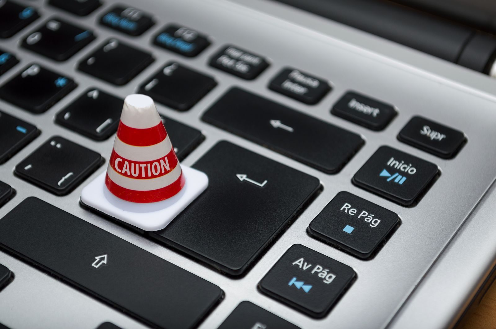 A small caution cone sitting on a laptop keyboard, a warning about cruise email scams