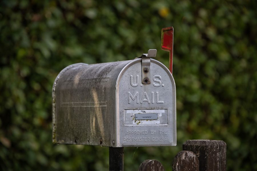 A traditional US mailbox with its red flag raised